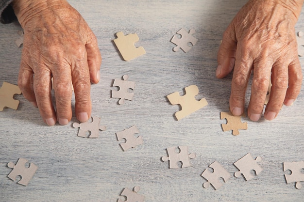 Foto mani di vecchie donne con un puzzle