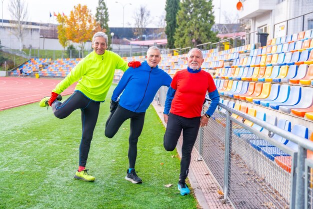 Photo old fiends warming up in a running track in winter