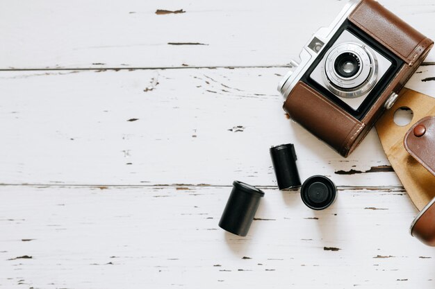 茶色のビンテージケースの古いフィルムカメラと木製の背景の上のフィルムのロールtopviewx9xA