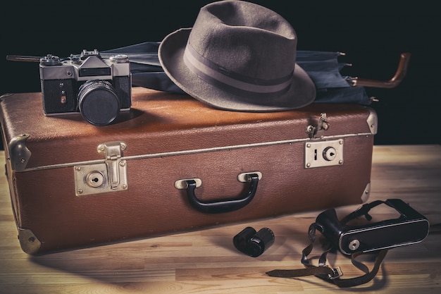 Old film camera with vintage hat and umbrella on old suitcase neat film and camera case