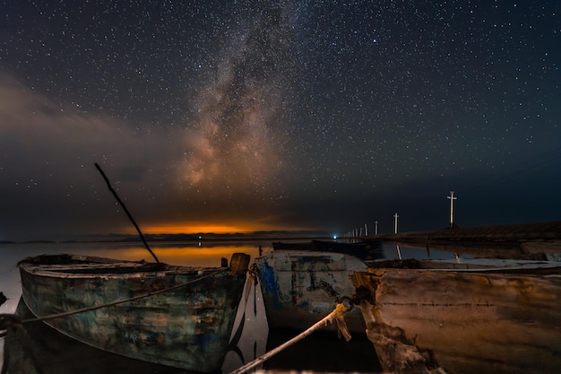 밤에는 알바니아의 호수에 있는 오래된 시 보트, 은하계에 있는 별빛 하늘