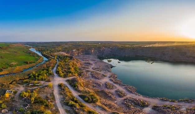 Old flooded stone quarry with large stones in the evening warm bright light covered with small dry plants in picturesque ukraine