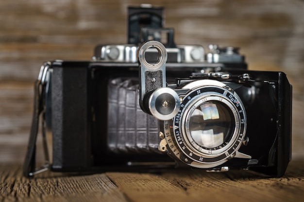 Old folding camera on a textured rustic wooden surface.