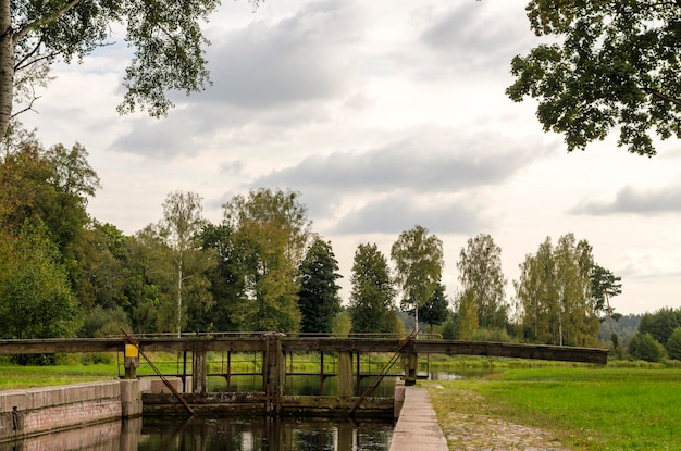 Old gateway on the channel Wooden dam on the river Autumn landscape