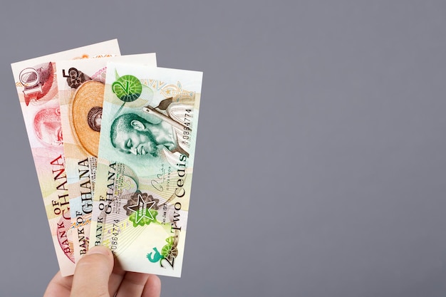 Photo old ghanaian money cedi in the hand on a gray background