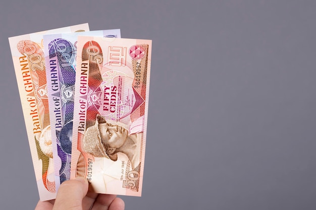 Photo old ghanaian money cedi in the hand on a gray background