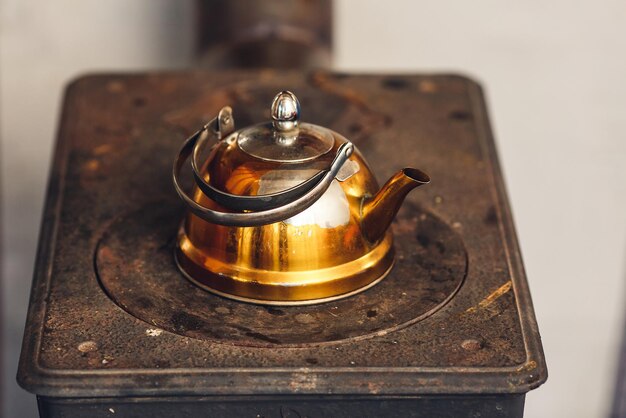 Old gilded kettle on an iron stove.