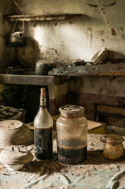 Old glass bottle and jar on table in abandoned kitchen