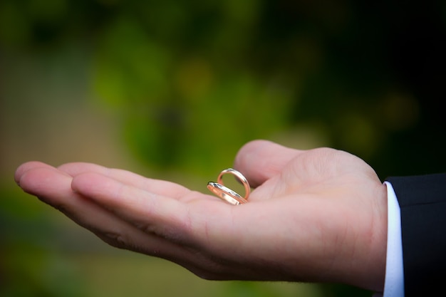 Vecchie fedi nuziali dorate sulla mano di un uomo