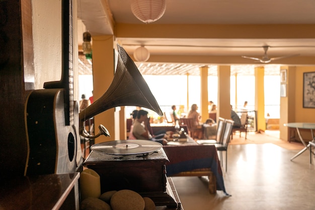 Old gramophone, guitar and people in restaurant, focus on gramophone, close up