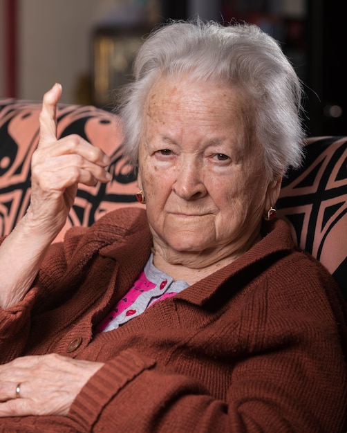 Old grayhaired woman in angry gesture posing at home