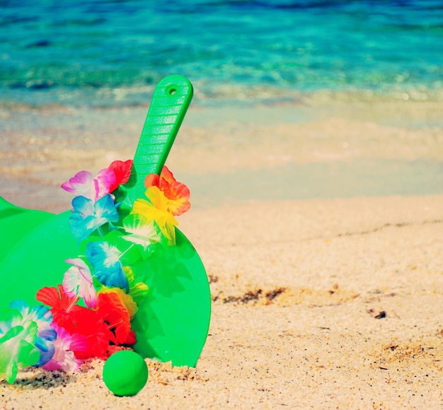 Old green rackets with hawaiian necklace by the sea