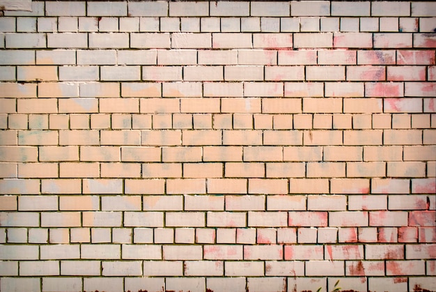 Old grunge painted brick wall texture with delicate vignetting.