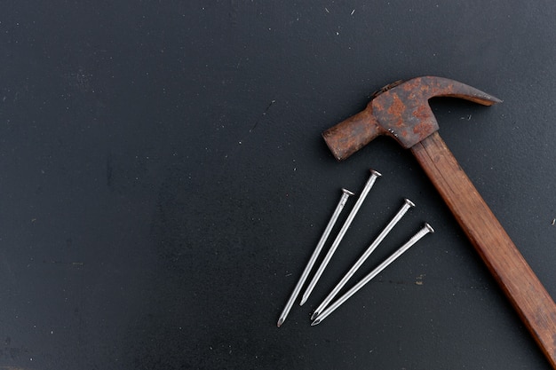 Old hammer and iron nail on black wood 