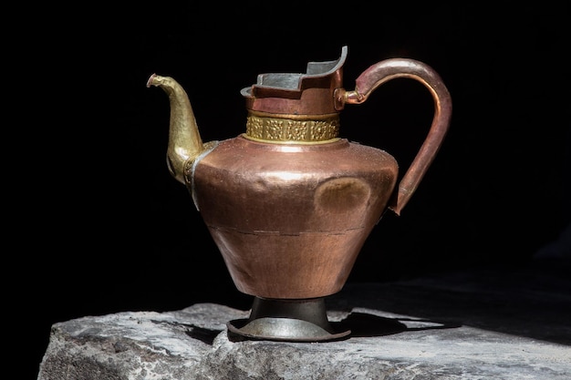 Old handmade tibetan pitcher on black background close up IndiaLadakh