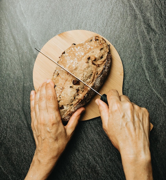 Old hands preparing freshly baked artisan and organic bread over a rustic table Homemade cooking Sourdough bread with crispy crust on wooden shelf Bakery goods concept Restaurant and goods