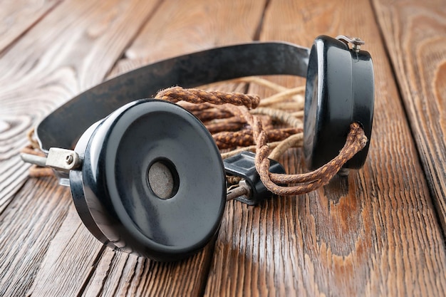 Old headphones Vintage headphones with a cloth wire on a wooden background