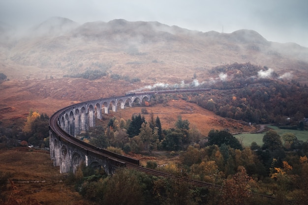 Photo old historical steam train riding on famous viaduct bridge travel and tourist destination in europe ...