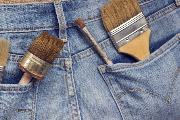 Old home repair tools in jeans pockets.