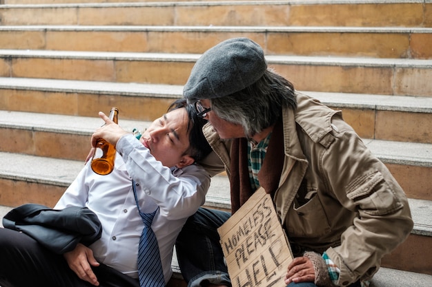 노숙자들은 술병으로 사업가의 문제를 듣고 있습니다.
