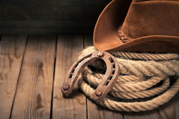 Old horseshoe , lariat lasso and cowboy hat on background