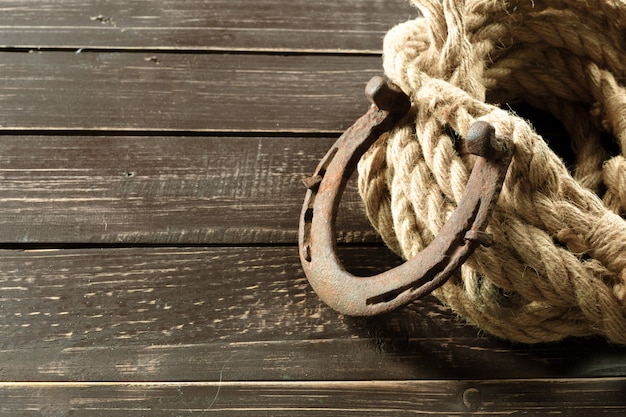 Old horseshoe and rope on wooden boards