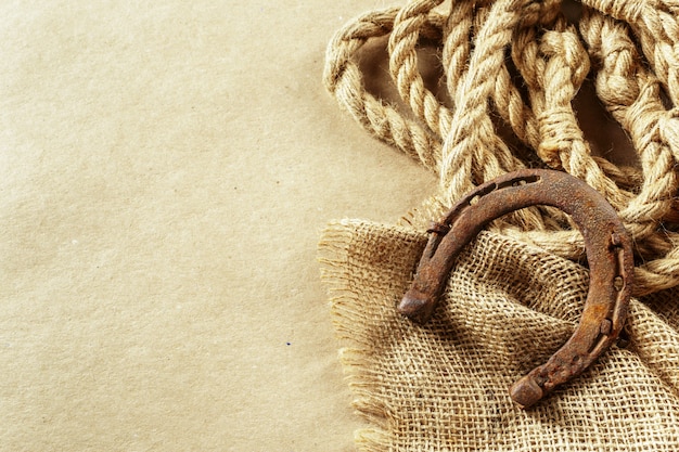 Old horseshoe and rope on wooden boards