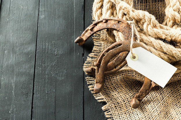 Old horseshoe and rope on wooden boards