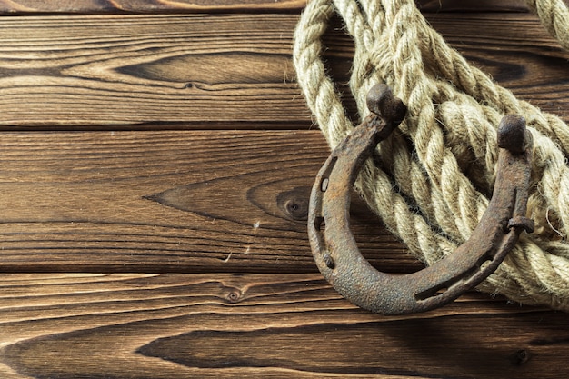 Old horseshoe and rope on wooden boards