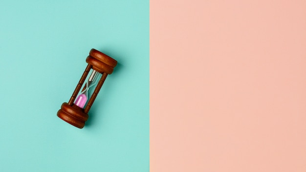 Old hourglass on blue and pink background