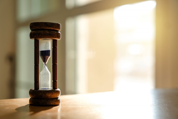 Old hourglass on wooden table