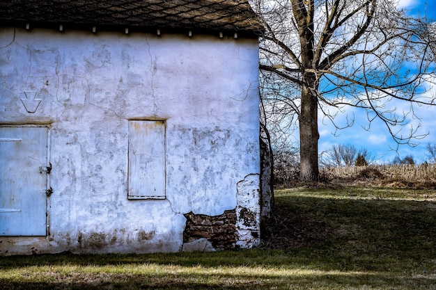 Foto vecchia casa vicino a un albero nudo sul campo contro il cielo