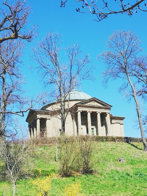 Old house on field against clear blue sky