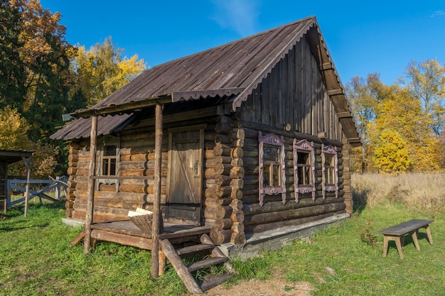 Фото Старый дом бревна в русской деревне. скамейка во дворе.