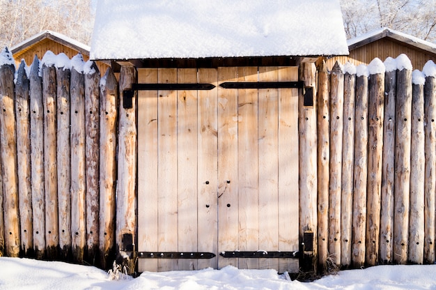 Старый дом в сибирском лесу огорожен частоколом снега