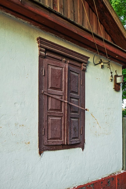 Photo an old house with a white wall whose window is covered with wooden shutters ukraine