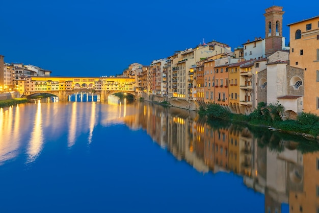 Old houses and tower on the embankment of the river arno and ponte vecchio at night florence tuscany