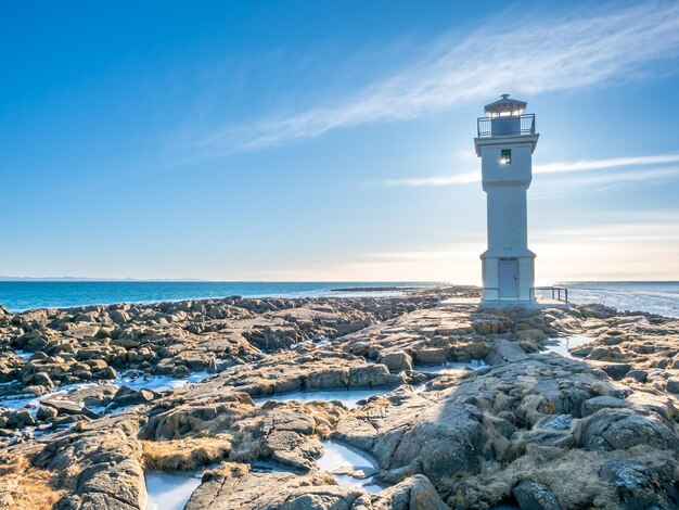 The old inactive Arkranes lighthouse at end of peninsula was built since 1918 under blue sky Iceland