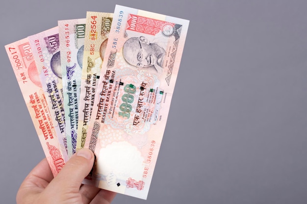 Old Indian money rupee in the hand on a gray background