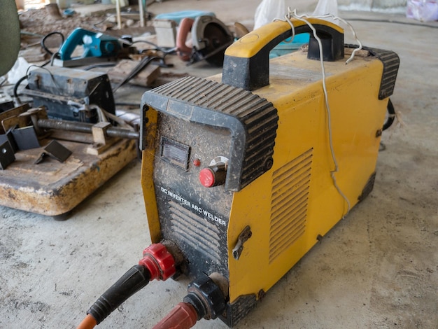 The old inverter welding machine on the concrete floor for use in the home improvement project front view with the copy space