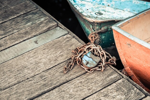 Old iron frayed and shabby boat noses tied to wooden dock