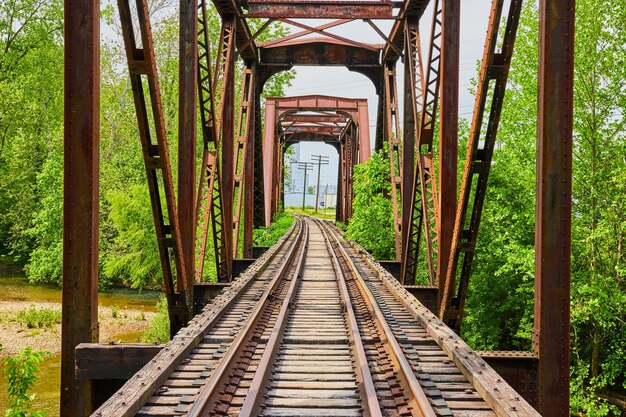 Old iron railroad bridge with train tracks curving away into distant city