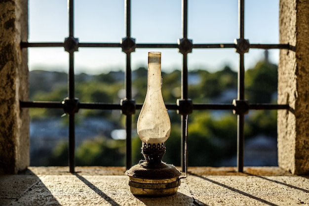 Old kerosene lamp near the window in the castle sunset grate