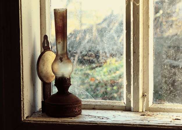古い素朴なレトロとヴィンテージの窓に古い灯油ランプ