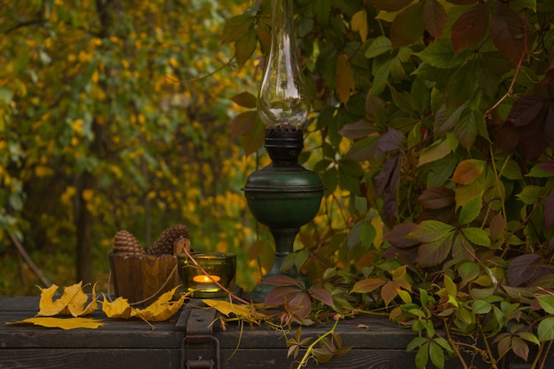 Old kerosene lamp on an old wooden surface in the autumn garden 