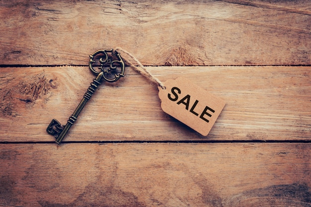 Old key with tag and text sale on wooden