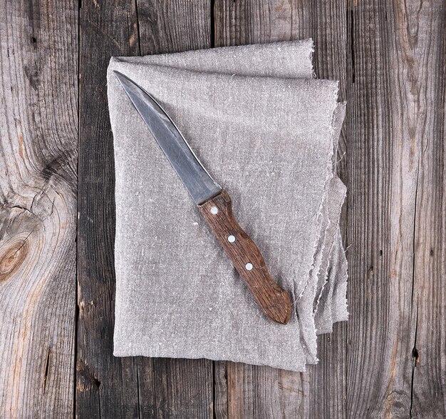 Foto vecchio coltello da cucina su uno sfondo di legno a tovagliolo grigio