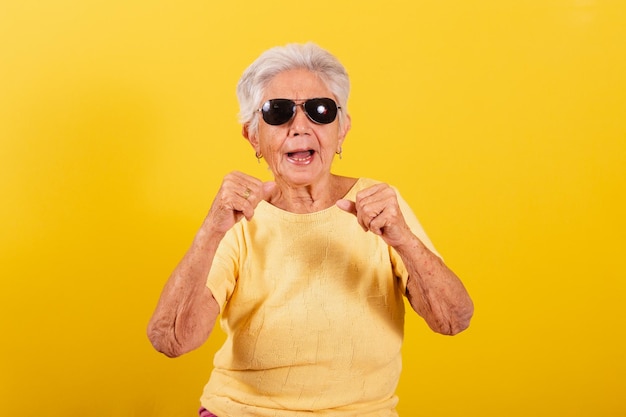 L'anziana signora che indossa occhiali da sole è alla moda per festeggiare feste e vibratore che urla di sì