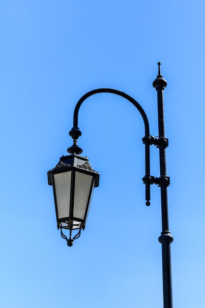 Old lantern on a metal post against blue sky