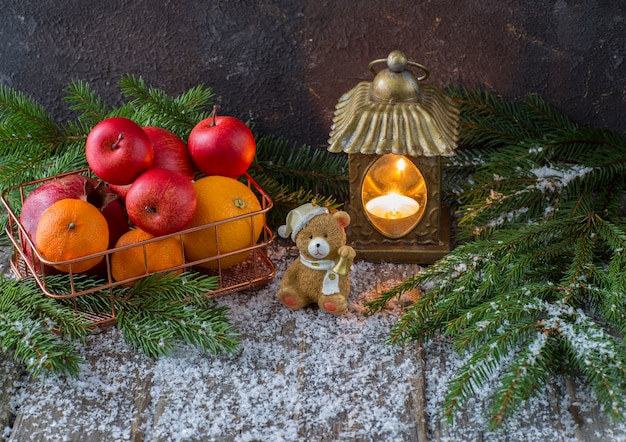 Old lantern, a toy bear, snow and a fruit basket